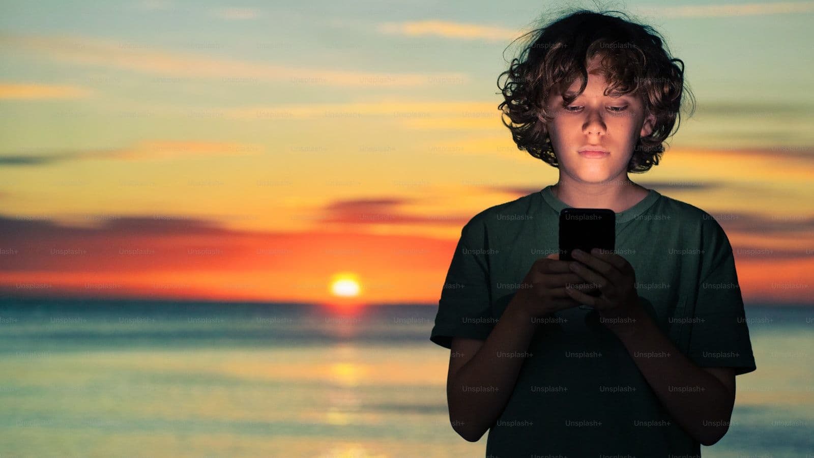 אדם צעיר מחזיק טלפון מול שקיעה — אינסל וניתוח קר של הנרטיב