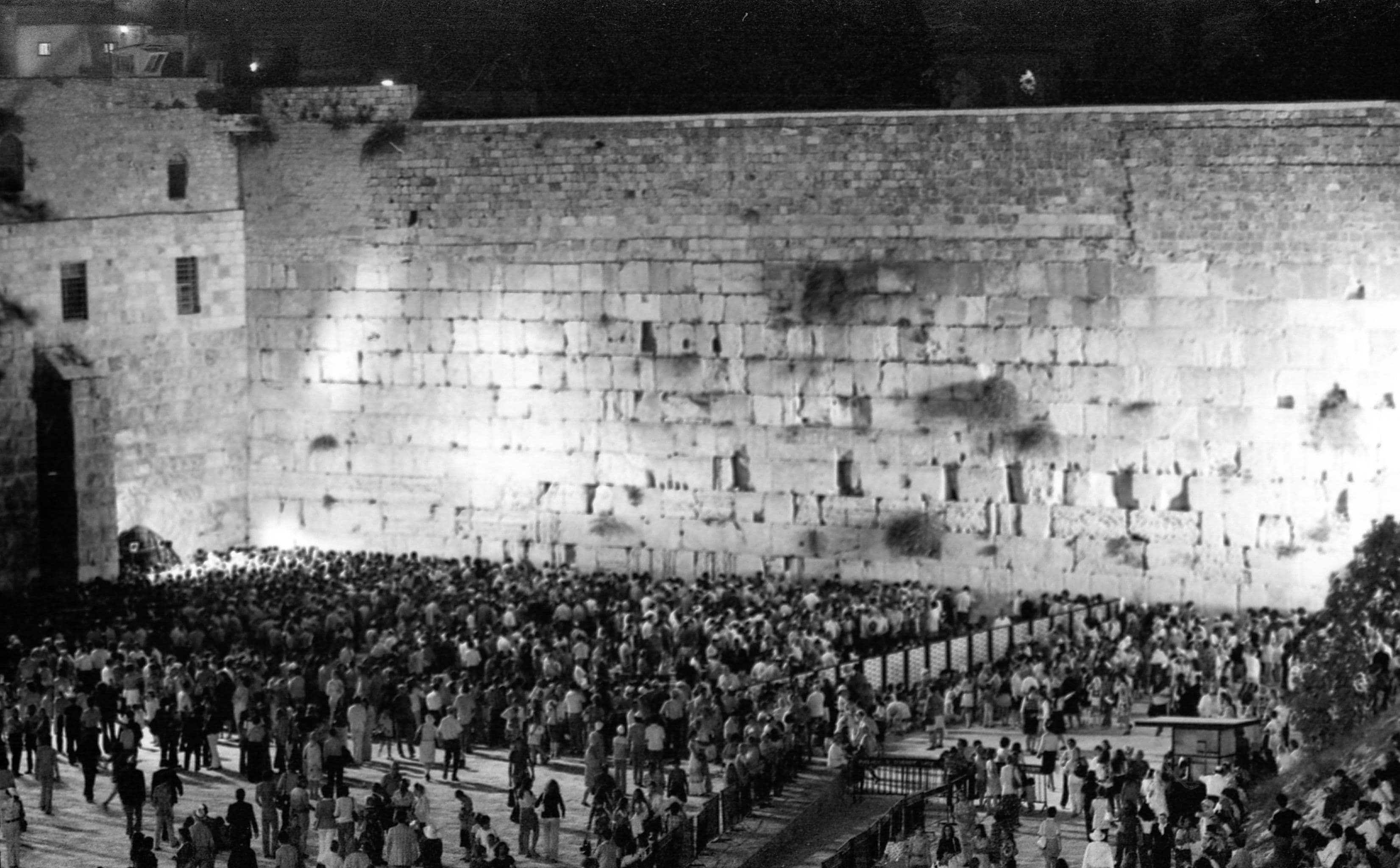 מתפללים בכותל המערבי בתשעה באב, 1973 — אב ובנו יושבים על הרצפה באבל בתוך המוני מתפללים